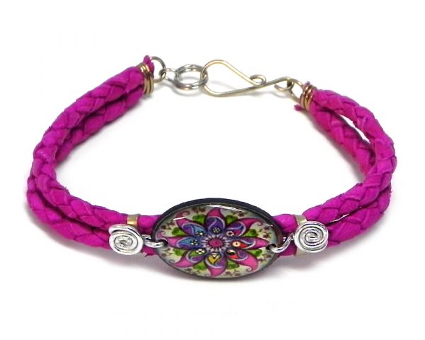 Handmade braided dyed leather bracelet with silver metal wire and oval-shaped acrylic New Age themed floral mandala graphic design centerpiece in magenta pink and multicolored color combination.