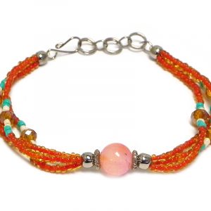 Handmade seed bead and crystal bead multi strand bracelet with tumbled orange agate gemstone crystal ball bead centerpiece in orange, mint green, and pearl white color combination.