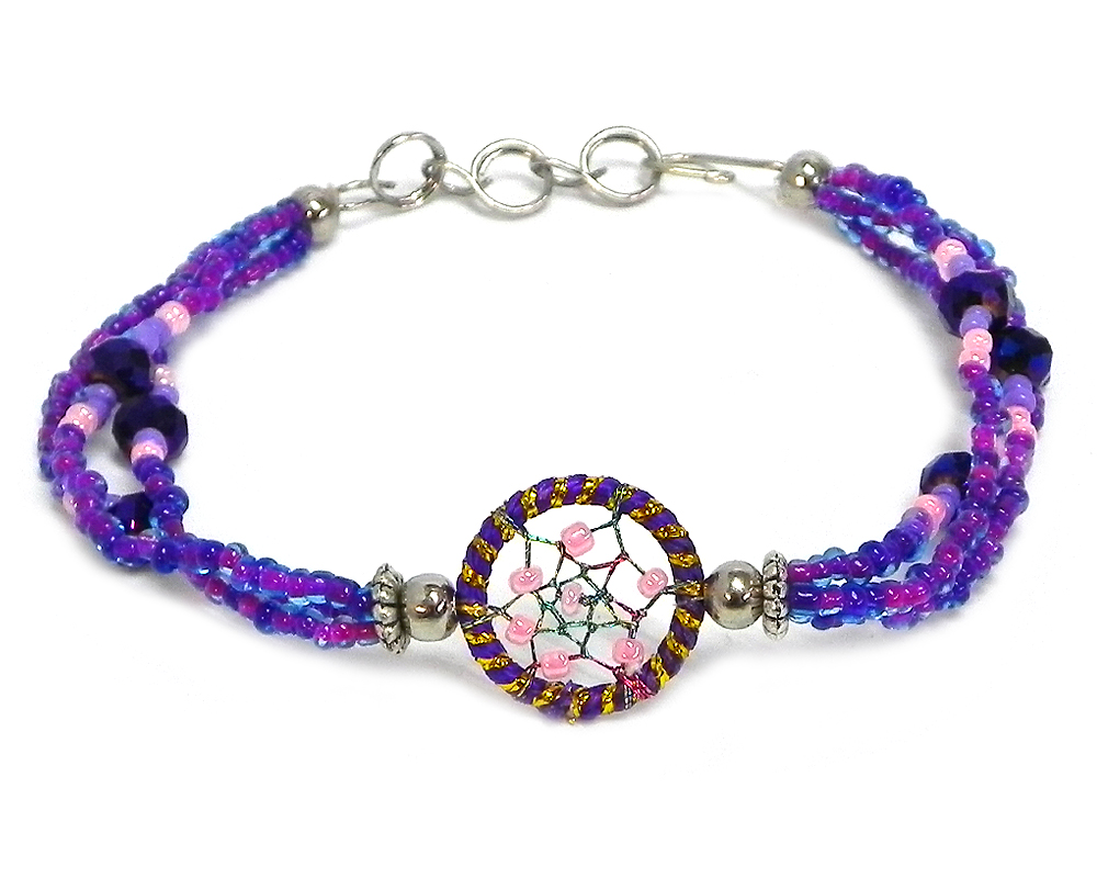 Handmade seed bead and crystal bead multi strand bracelet with round beaded sparkle thread dream catcher centerpiece in purple, gold, dark purple, and light pink color combination.
