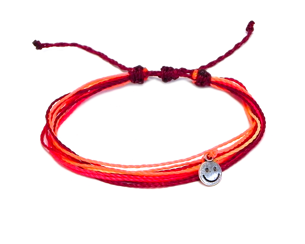 Handmade multicolored multi strand string pull tie bracelet with silver metal smiley face charm dangle in red, neon hot pink, neon salmon pink, and beige color combination.