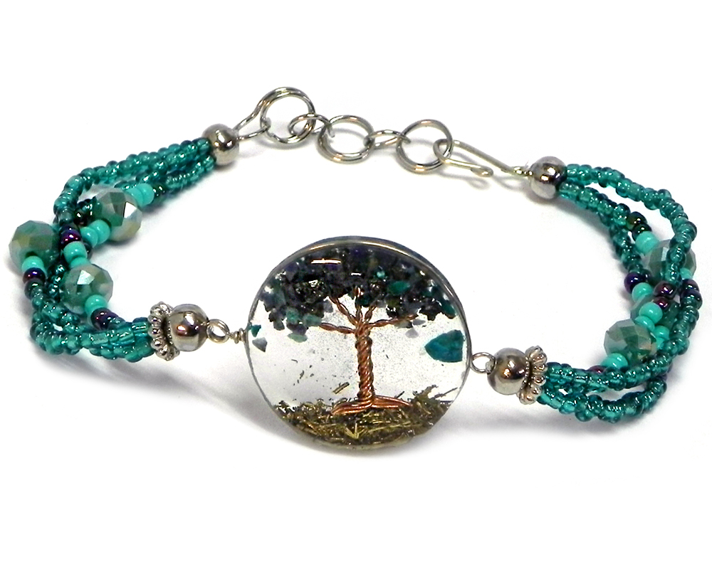 Handmade crystal bead and seed bead multi strand bracelet with round-shaped clear acrylic resin, copper wire, and crushed chip stone inlay tree of life centerpiece in teal green, turquoise mint, and iridescent navy blue color combination.