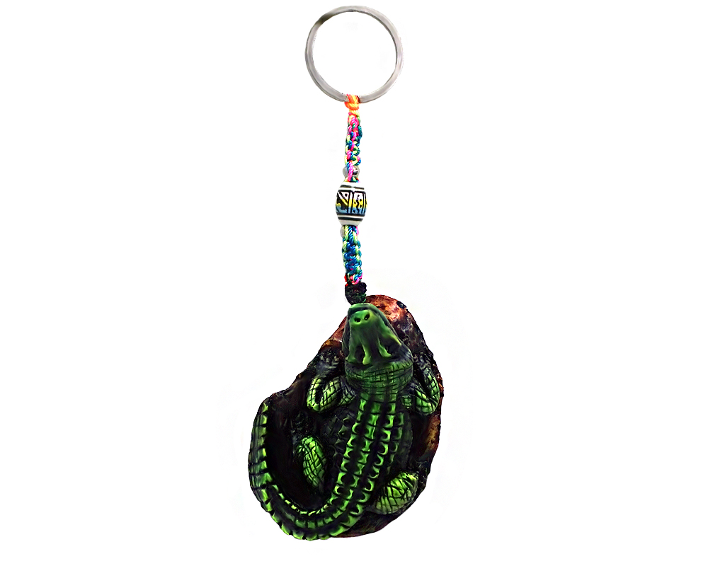 Handmade durepox resin figurine keychain of a green alligator on a rock.