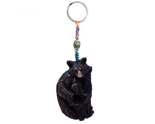 Handmade durepox resin figurine keychain of a raccoon on a tree.