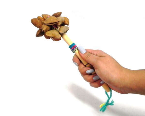 Handmade bamboo wooden stick rattle shaker music instrument with cacho seed pods and a cotton strap on handle.