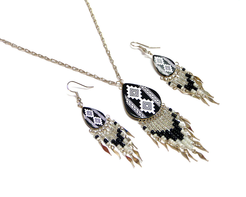 Handmade teardrop-shaped ceramic chain necklace and matching earrings with handpainted tribal pattern design and long seed bead and alpaca silver metal dangles in white, black, and clear color combination.