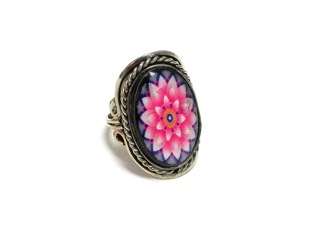 Handmade oval-shaped acrylic New Age themed floral mandala graphic design on alpaca silver metal ring with rope edge border in light pink, hot pink, blue, and golden yellow color combination.