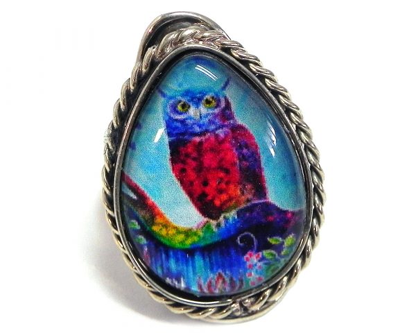 Handmade teardrop-shaped acrylic New Age themed owl graphic design on alpaca silver metal ring with rope edge border in tuquoise, blue, hot pink, and rainbow color combination.