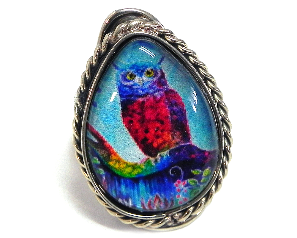 Handmade teardrop-shaped acrylic New Age themed owl graphic design on alpaca silver metal ring with rope edge border in tuquoise, blue, hot pink, and rainbow color combination.