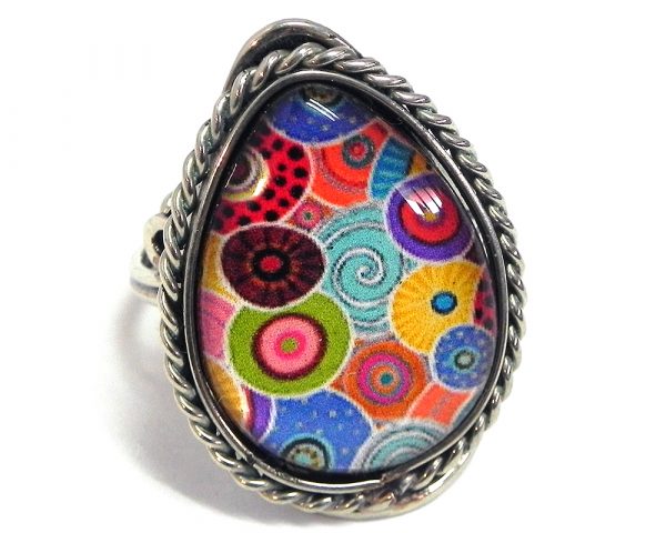 Teardrop-shaped acrylic New Age themed circle pattern graphic design on alpaca silver metal ring with rope edge border in multicolored color combination.