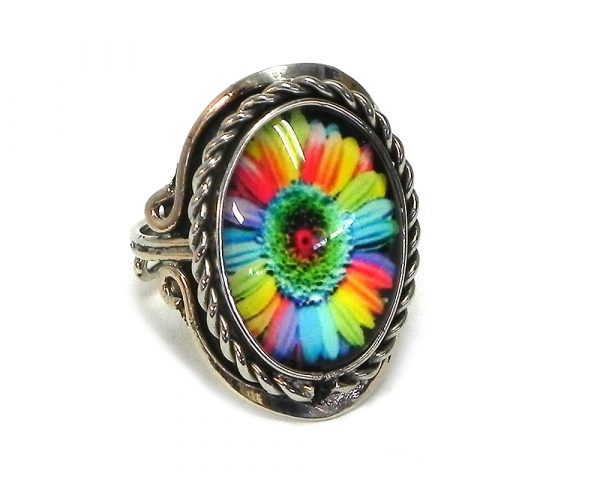 Handmade small oval-shaped acrylic New Age themed daisy flower graphic design on alpaca silver metal ring with rope edge border in rainbow color combination.