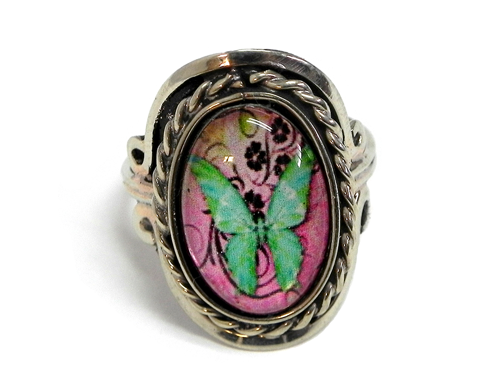 RG-060101074434 Handmade small oval-shaped acrylic vintage themed butterfly graphic design on alpaca silver metal ring with rope edge border in pink, mint, lime green, and black color combination.