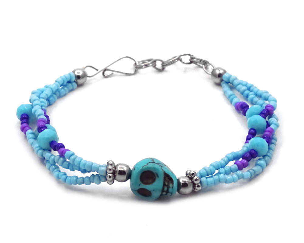 BR-020904150656 Handmade bead and crystal bead multi strand bracelet with skull shaped tumbled magnesite gemstone crystal centerpiece in light blue, turquoise, purple, and indigo color combination.