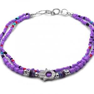 Handmade seed bead multi strand anklet with silver metal hamsa hand charm and tribal pattern bead centerpiece in purple, red, and mint turquoise color combination.