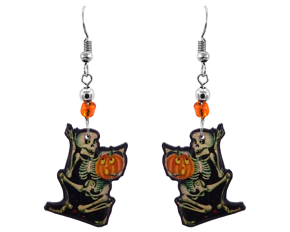 EA-043711380902 Handmade Halloween themed skeleton holding pumpkin graphic acrylic dangle earrings with beaded metal hooks in beige, black, orange, and yellow color combination.