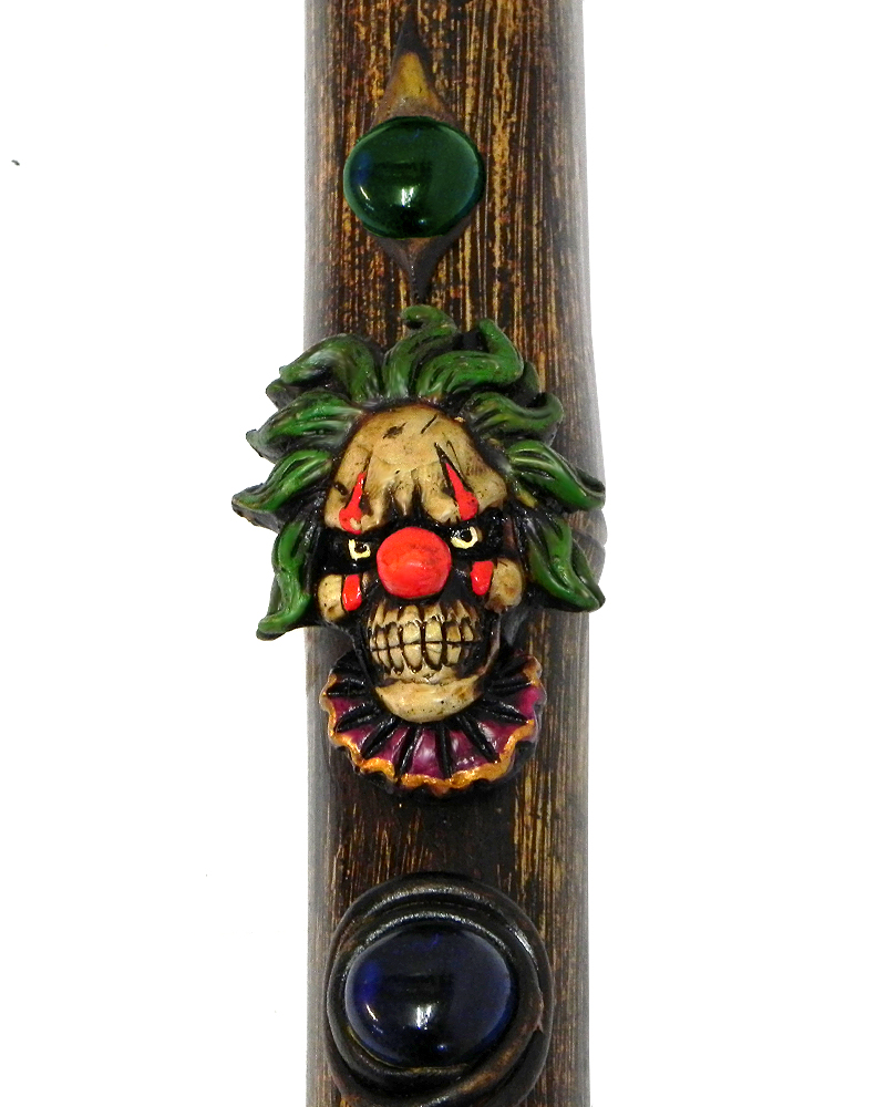 Handcrafted tobacco smoking natural bamboo wooden peace pipe of an evil clown head with a creepy smile and red nose.