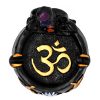 Handcrafted round incense holder ash tray with a gold om sign, lotus design, and a black 3D figurine of a meditating body with 7 chakra rainbow-colored tumbled gemstone crystals.