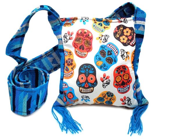 Handmade small square-shaped padded crossbody purse bag with woven tribal print striped pattern, multicolored floral Day of the Dead sugar skull design, and fringe in white, red, turquoise blue, golden yellow, and black color combination.