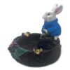 Handcrafted round incense holder ash tray with a flower and leaf design and 3D figurine of a rabbit holding money in turquoise, green, black, and gold color combination.